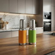 Two stainless steel thermos bottles with orange and green sleeves on a wooden kitchen countertop